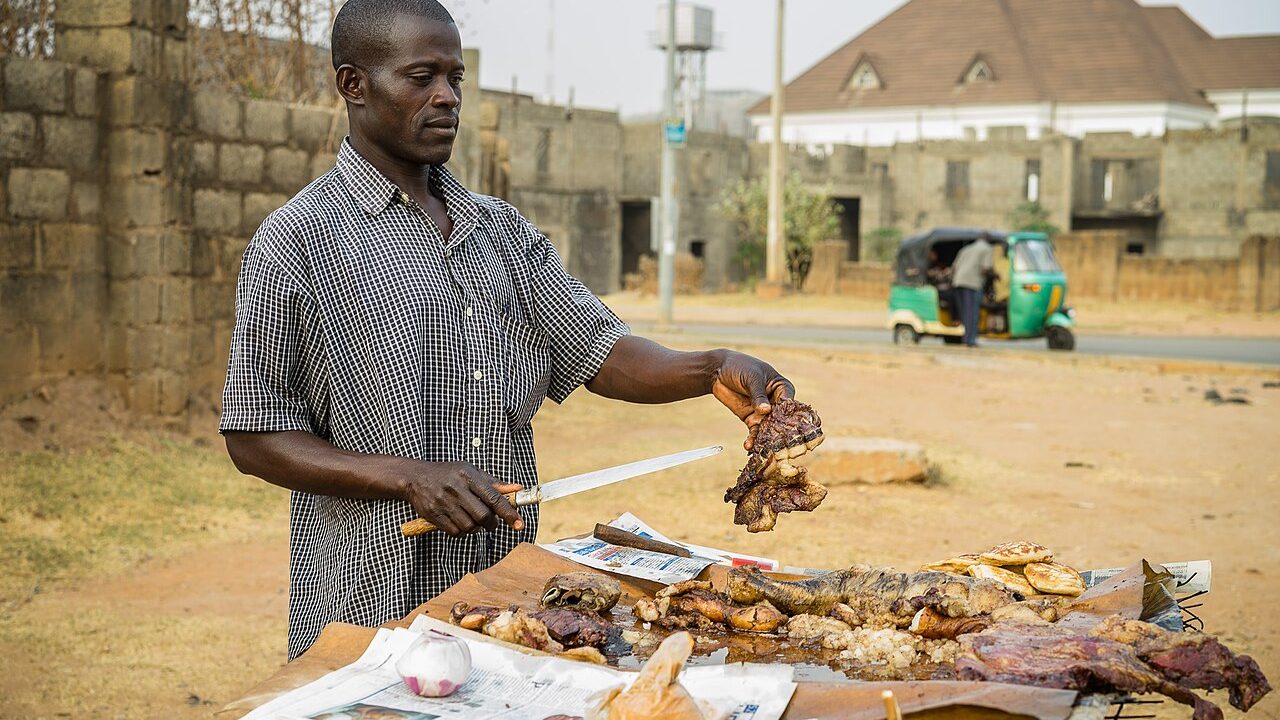 A suya seller at his grill