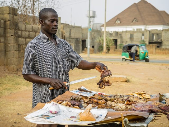 A suya seller at his grill